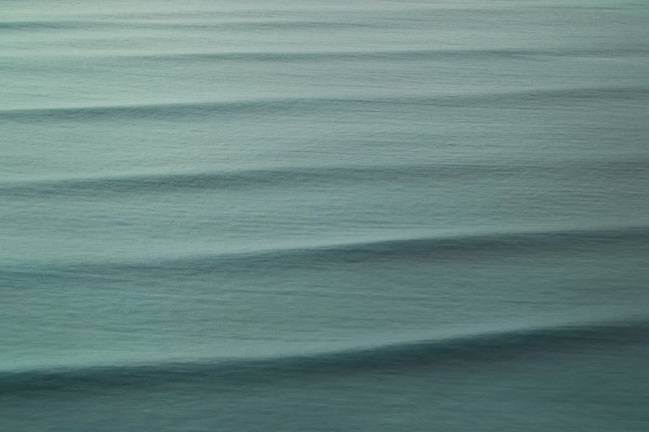 Gentle green swell lines on quiet water.