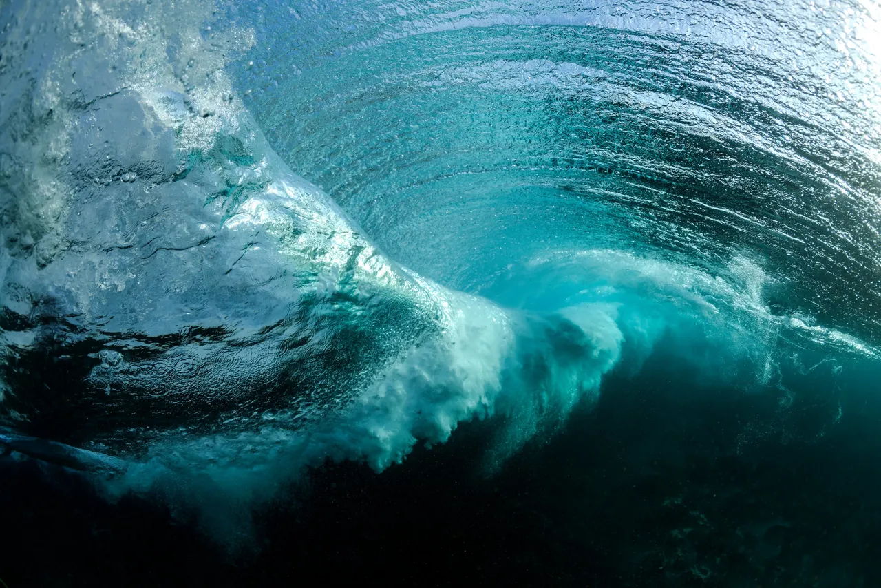 A heavy wave folding over in deep green and white water.